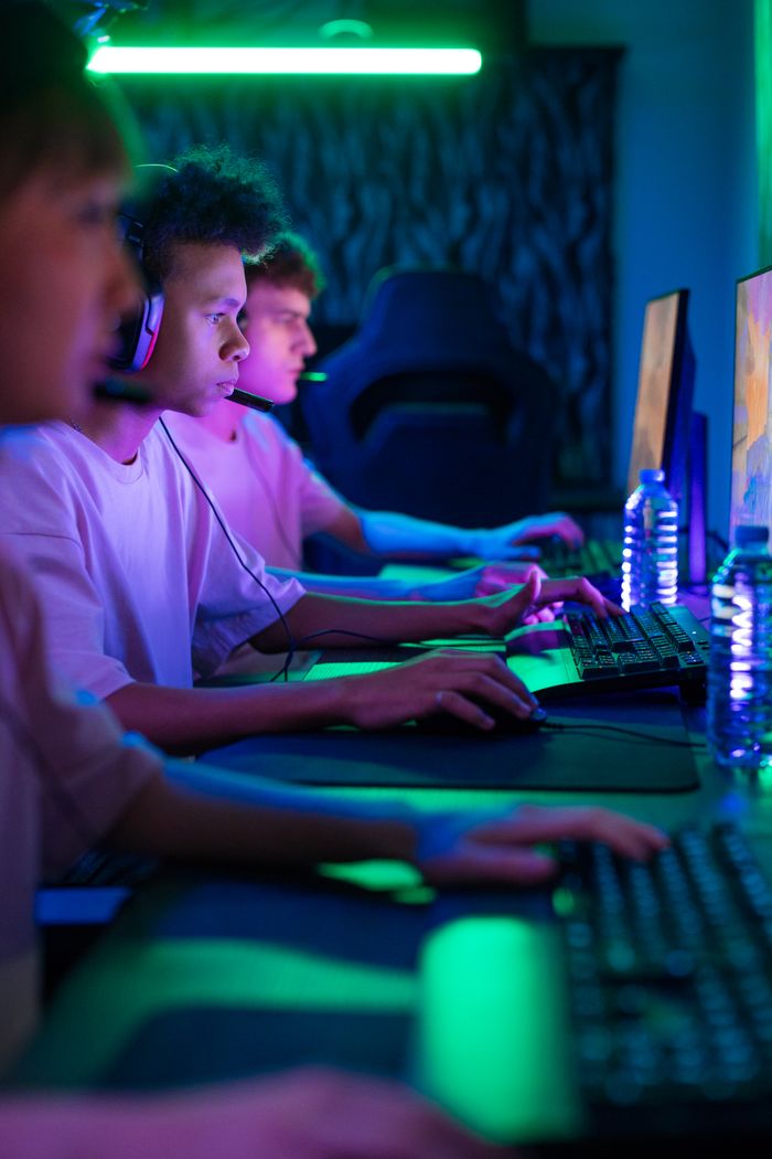 A group of young adults intensely focused on a gaming competition in a vibrant setting.